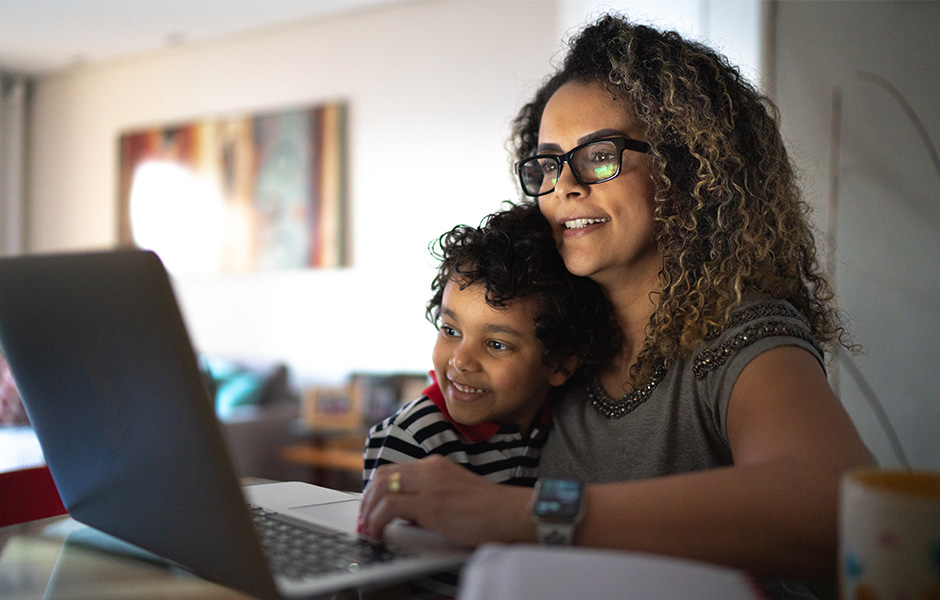 Close-up of smiling mom and smiling preschooler looking at laptop